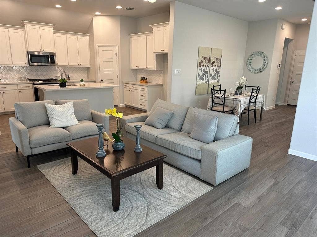 5308 Tupper Avenue, Fate, TX 75087 Open-concept living space featuring wood-finish flooring, recessed lighting, and a kitchen with white cabinetry, a center island, and stainless steel appliances