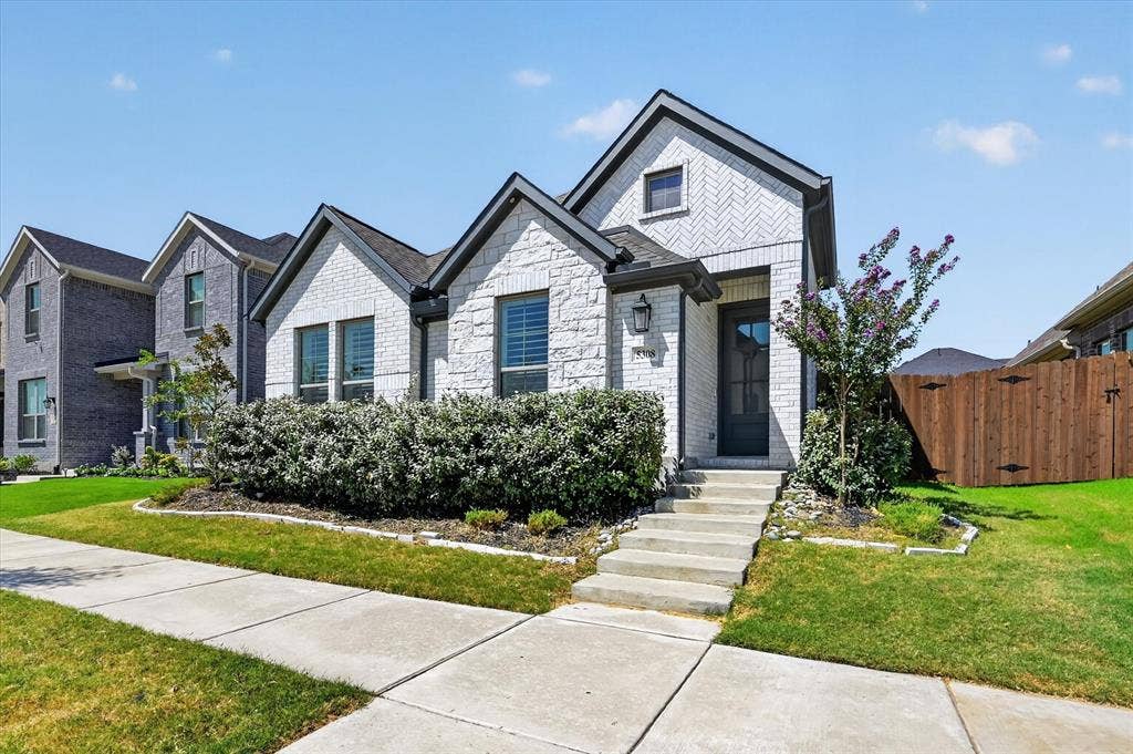 5308 Tupper Avenue, Fate, TX 75087 White brick exterior with dark trim accents, concrete front walkway, landscaped front yard, and dark-paneled front door