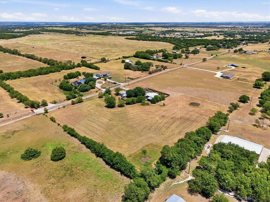 TBD Lot 1 Bluebonnett Lane, Lorena, TX 76655 Expansive acreage with established tree lines, a paved road, and visible structures, featuring clear land