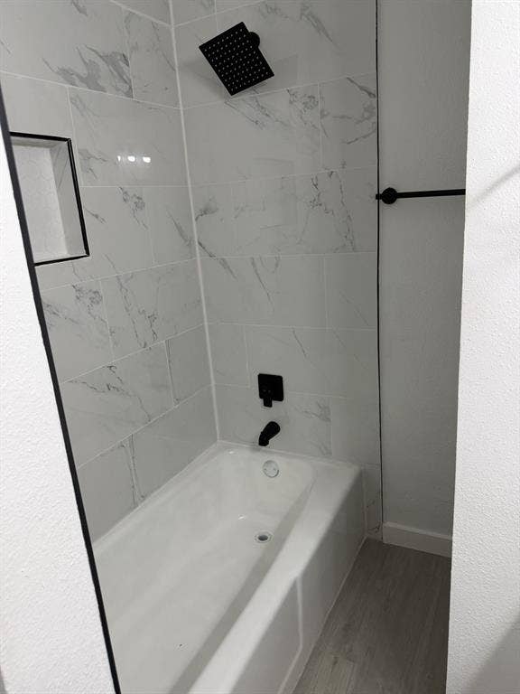 806 S Atkerson Lane, Euless, TX 76040 Bathtub with tiled surround, matte black fixtures, and a recessed shower niche