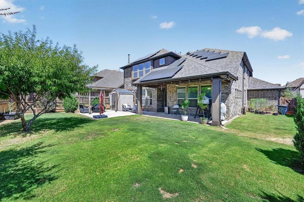 316 Jernigan Drive, Euless, TX 76040 Expansive backyard featuring a stone and brick exterior, covered patio, solar panels, and a concrete patio surface