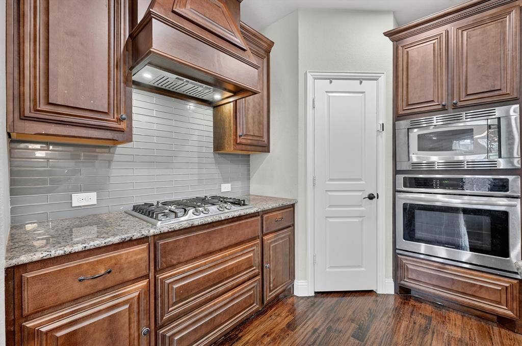 316 Jernigan Drive, Euless, TX 76040 Wood-finish flooring, dark wood cabinetry, stainless steel oven, stainless steel microwave, and a gas cooktop
