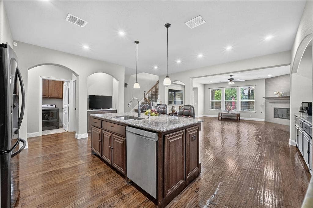 316 Jernigan Drive, Euless, TX 76040 Kitchen island with granite countertop, integrated stainless steel dishwasher, and under-mount sink, complemented by wood-finish flooring