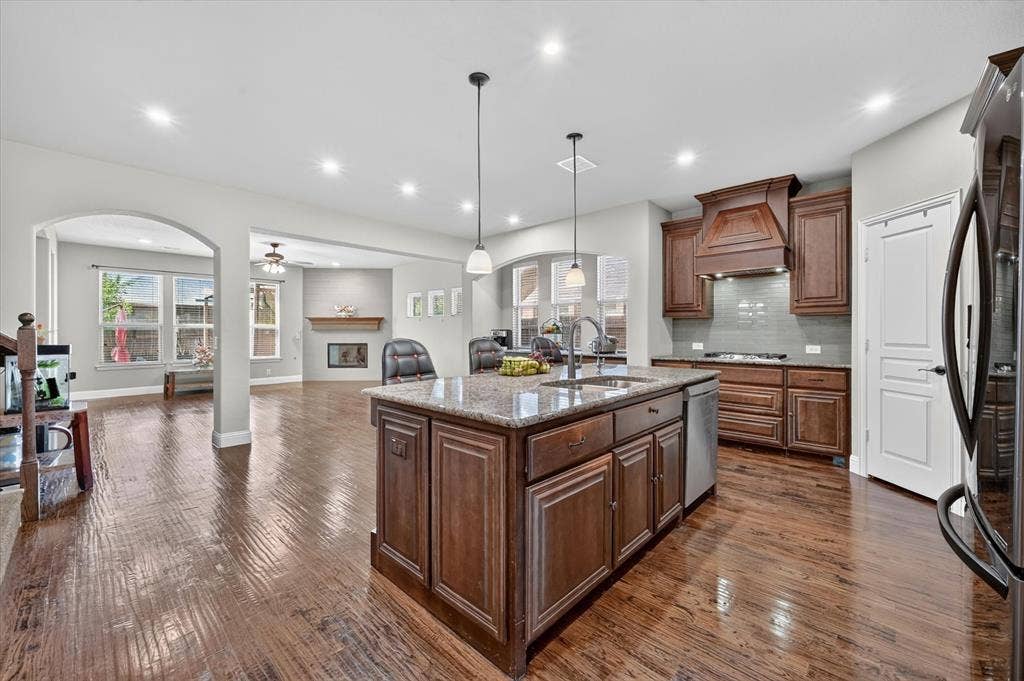316 Jernigan Drive, Euless, TX 76040 Kitchen island with granite countertops, rich wood cabinetry, stainless steel appliances, and wood-finish flooring