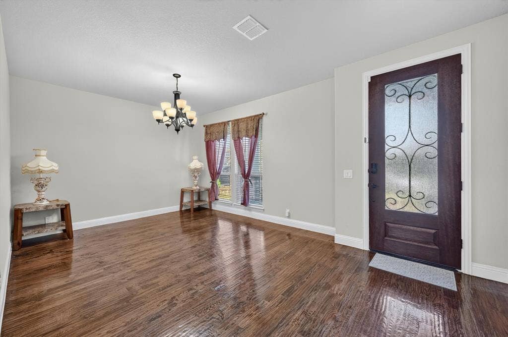 316 Jernigan Drive, Euless, TX 76040 Dark wood-finish flooring, a decorative glass-paneled entry door, and a multi-arm chandelier