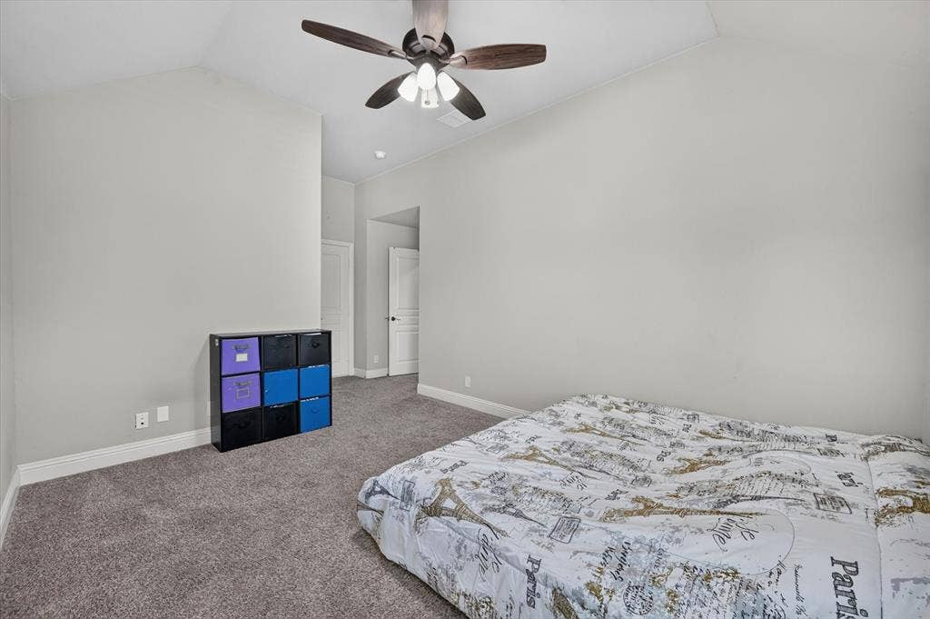 316 Jernigan Drive, Euless, TX 76040 Vaulted ceiling, light gray wall paint, dark wood-finish ceiling fan with integrated lighting, gray carpeting, and white trim