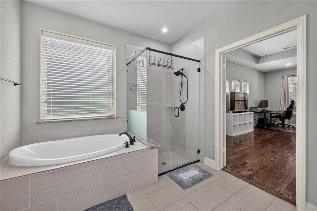 316 Jernigan Drive, Euless, TX 76040 Soaking tub with black fixtures, tile-surround shower with glass enclosure, white window blinds, and recessed lighting