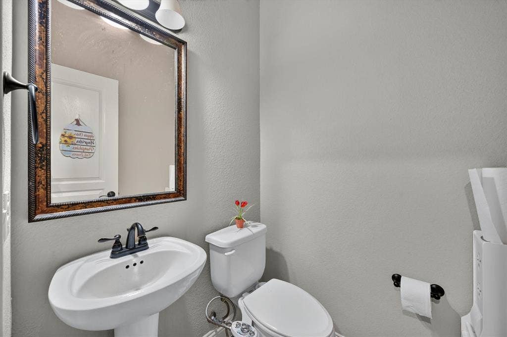 316 Jernigan Drive, Euless, TX 76040 Pedestal sink with dark-toned fixtures, rectangular framed mirror, and mounted vanity lighting