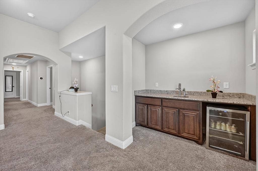 316 Jernigan Drive, Euless, TX 76040 Built-in wet bar featuring dark wood-finish cabinetry, a stainless steel sink, and a granite-style countertop