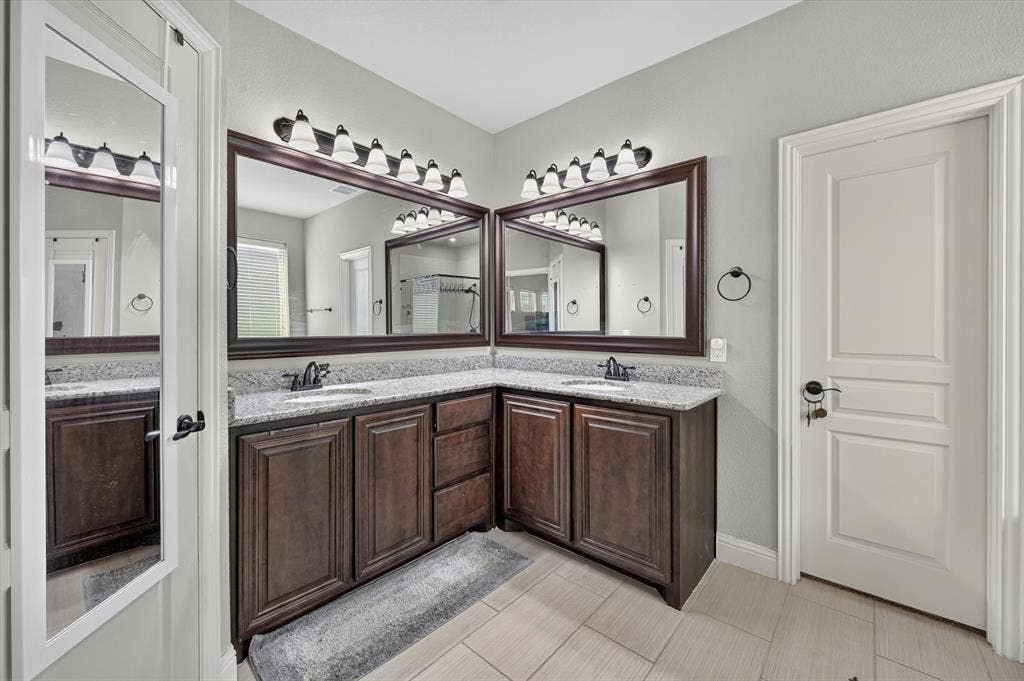 316 Jernigan Drive, Euless, TX 76040 Dual wood-finish vanities with light-colored countertops, framed mirrors, and tile flooring