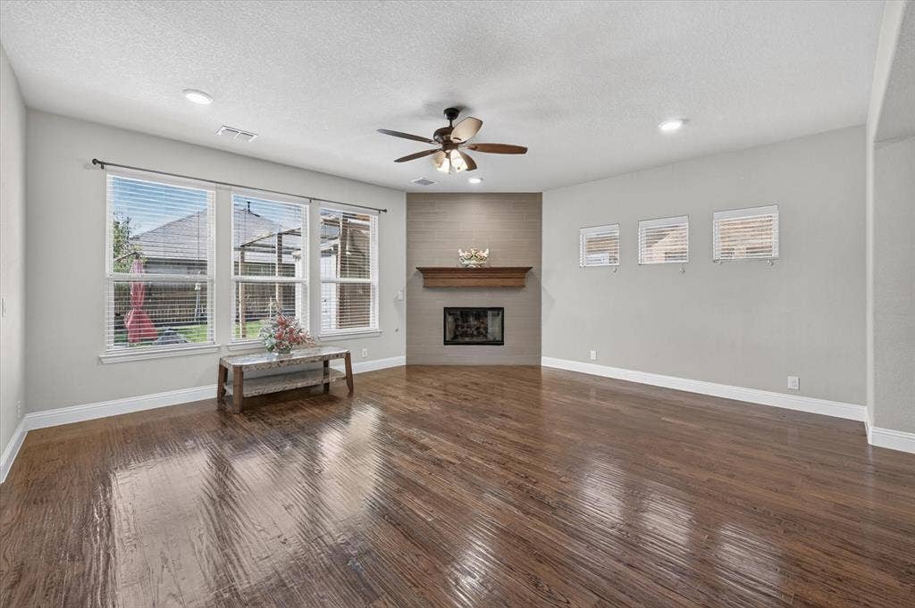 316 Jernigan Drive, Euless, TX 76040 Spacious living area featuring wood-finish flooring, a corner fireplace with a wood mantle and tile surround, recessed lighting, and a ceiling fan