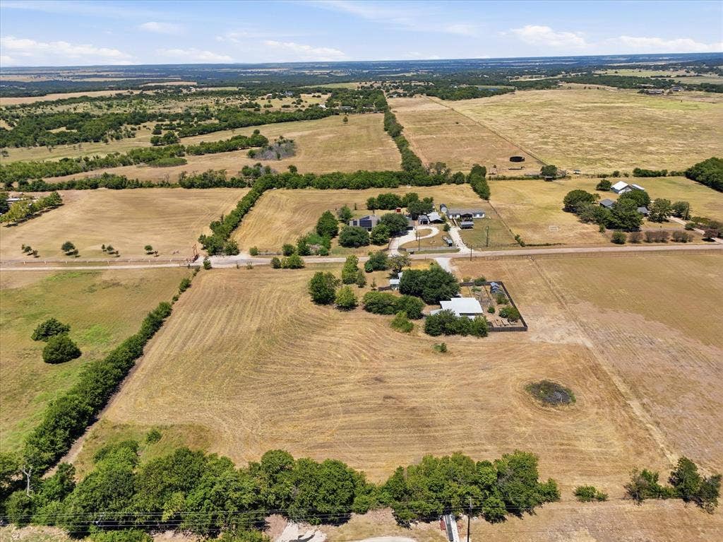 Expansive rural landscape featuring multiple parcels of land, established tree lines, and a visible pond
