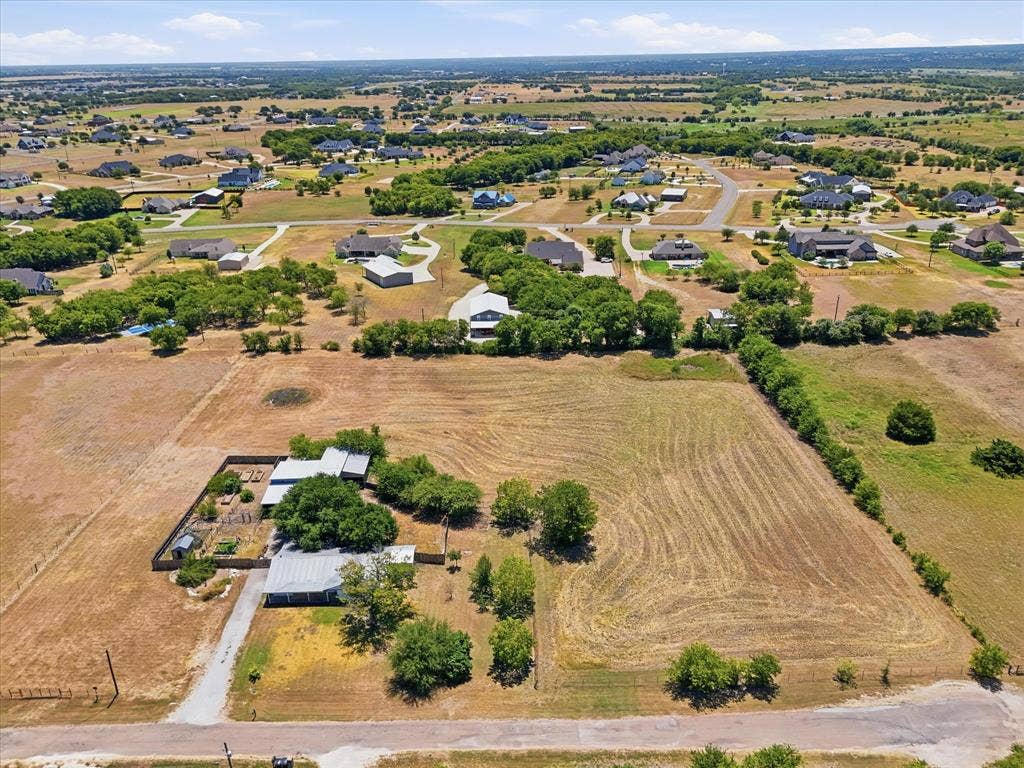 Expansive property with a gravel driveway, mature trees, and a fenced garden area