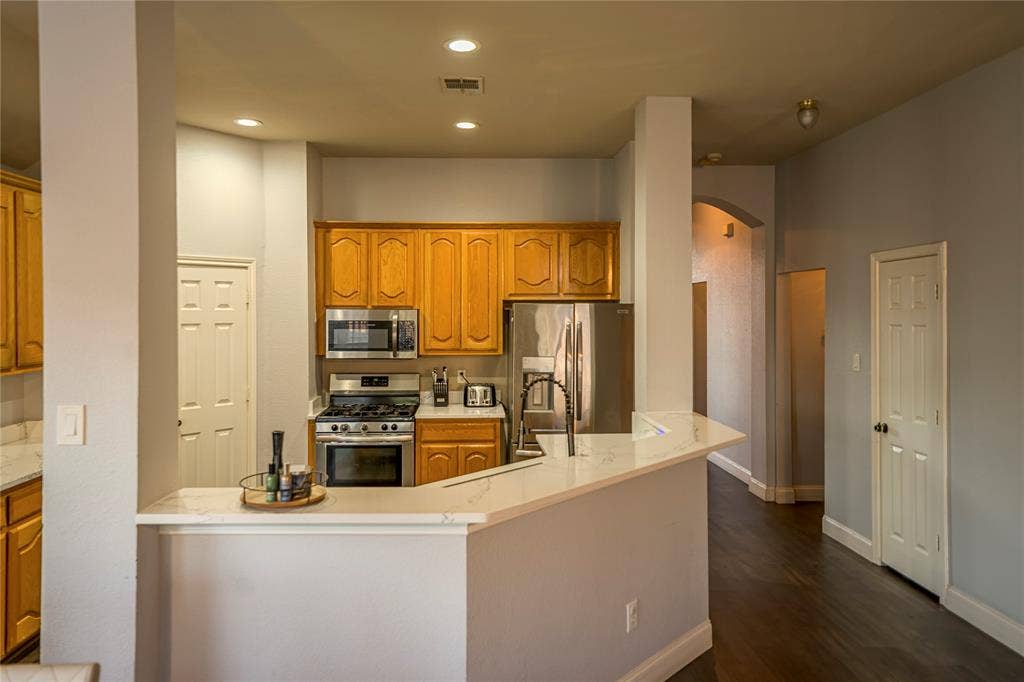Kitchen featuring wood cabinetry, stainless steel appliances, and a breakfast bar with a light-toned countertop