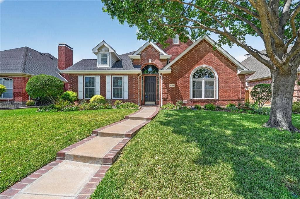 10307 Perkins Drive, Irving, TX 75063 Brick exterior with white window shutters and a decorative arched entryway