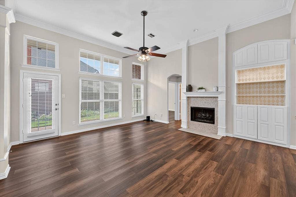 10307 Perkins Drive, Irving, TX 75063 Spacious living area featuring wood-finish flooring, a ceiling fan, a tiled fireplace with a mantel, and built-in cabinetry