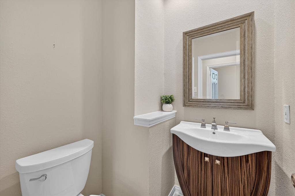 10307 Perkins Drive, Irving, TX 75063 Vanity with a curved wood-finish base, integrated white basin, and a framed mirror
