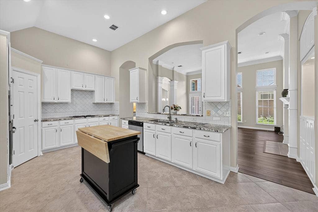 10307 Perkins Drive, Irving, TX 75063 Kitchen featuring white cabinetry, granite countertops, tile backsplash, and a movable island with a wood-finish top