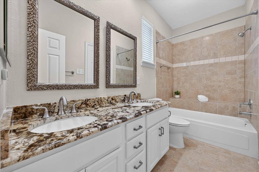 10307 Perkins Drive, Irving, TX 75063 Dual vanity with undermount sinks, stone countertop, and decorative framed mirrors