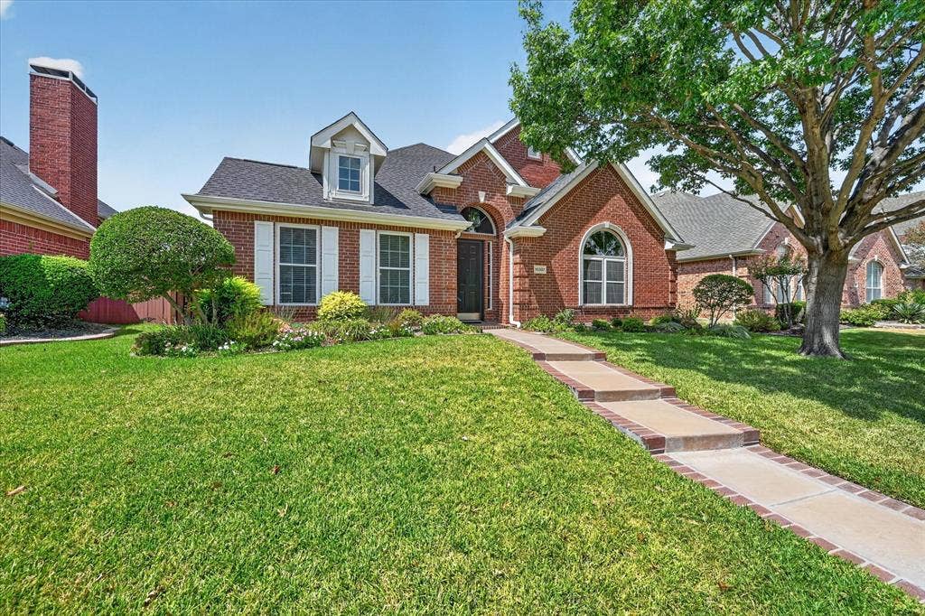 10307 Perkins Drive, Irving, TX 75063 Brick exterior with white window shutters and a gabled dormer