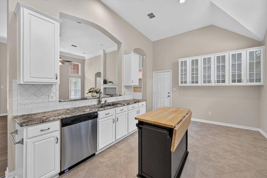 10307 Perkins Drive, Irving, TX 75063 Chef's kitchen featuring white cabinetry, granite countertops, stainless steel appliances, and a large center island with wood-finish countertop