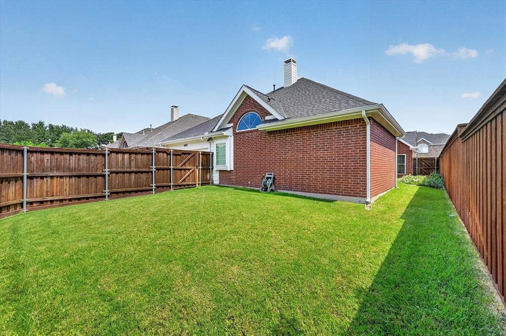 10307 Perkins Drive, Irving, TX 75063 Enclosed backyard featuring a wood fence, red brick exterior, and a side access gate