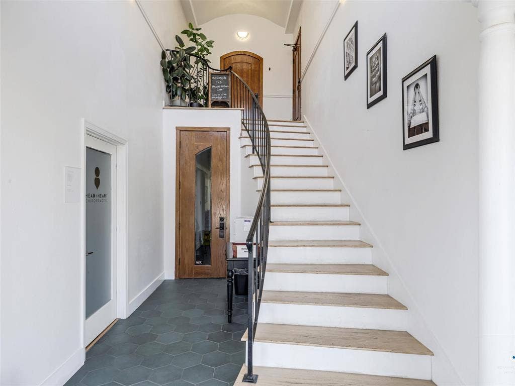 4310 Gaston Avenue, #103, Dallas, TX 75246 Hexagonal floor tiles, open staircase with dark metal railing, natural wood-finish doors, and white walls