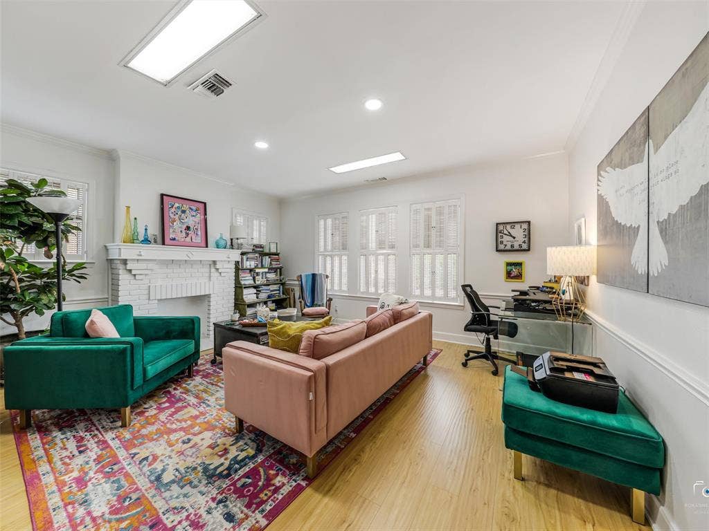 4310 Gaston Avenue, #103, Dallas, TX 75246 Wood-finish flooring, white brick fireplace, multiple windows with plantation shutters, recessed lighting, and crown molding