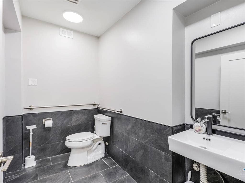 4310 Gaston Avenue, #103, Dallas, TX 75246 White wall-mounted sink with a rectangular mirror, dark tile wainscoting, and large format floor tiling