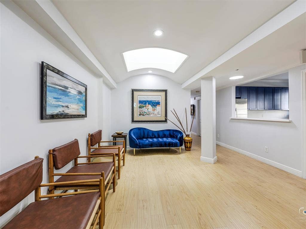 4310 Gaston Avenue, #103, Dallas, TX 75246 Recessed lighting throughout, arched ceiling detail, wood-finish flooring, and pass-through window to kitchen with blue cabinetry