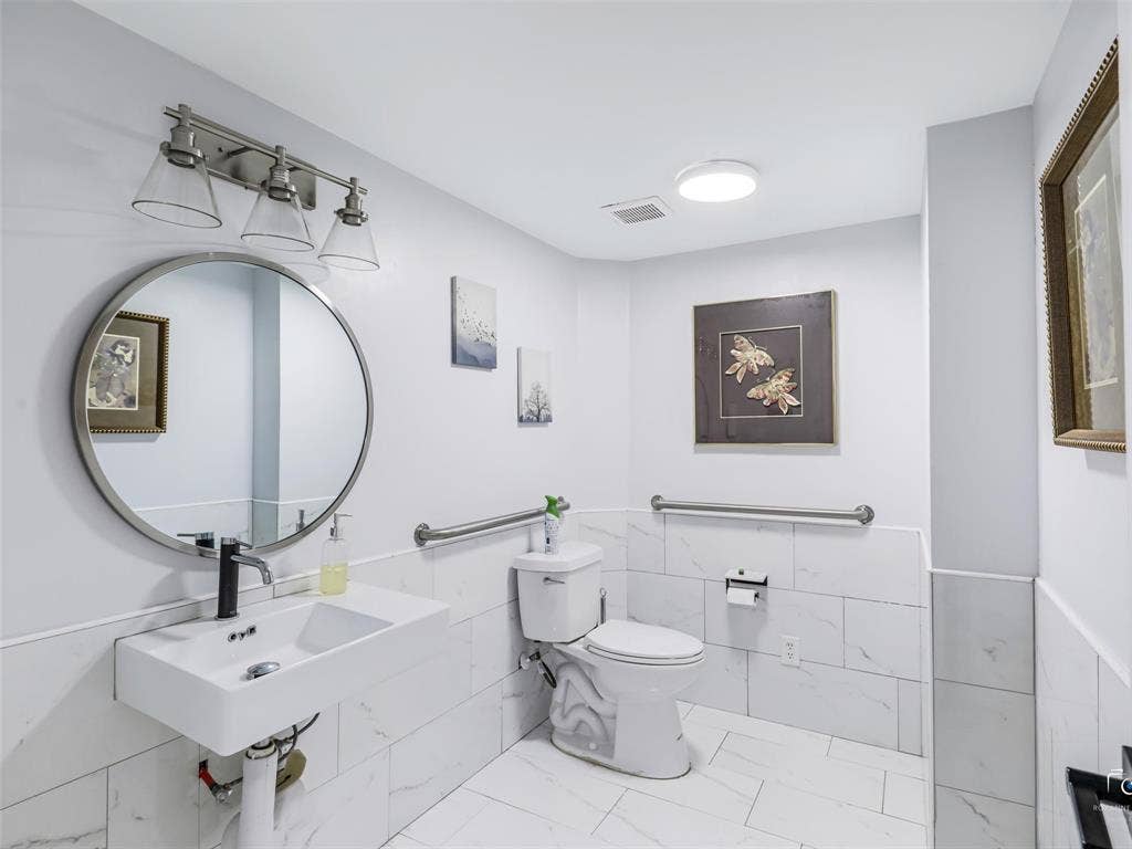 4310 Gaston Avenue, #103, Dallas, TX 75246 White wall-mounted sink, rectangular toilet, and wall-mounted lighting fixture