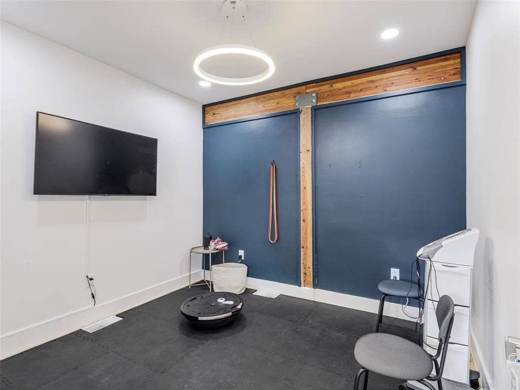4310 Gaston Avenue, #103, Dallas, TX 75246 White walls with an accent wall featuring a wood beam and vertical wood paneling