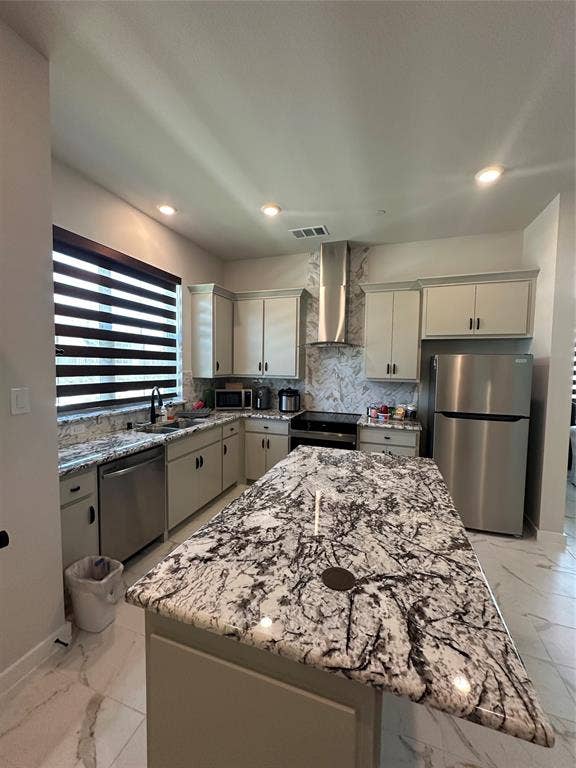 Spacious kitchen featuring an expansive island with a polished countertop, stainless steel appliances, upper and lower cabinetry, recessed lighting, and a coordinating backsplash