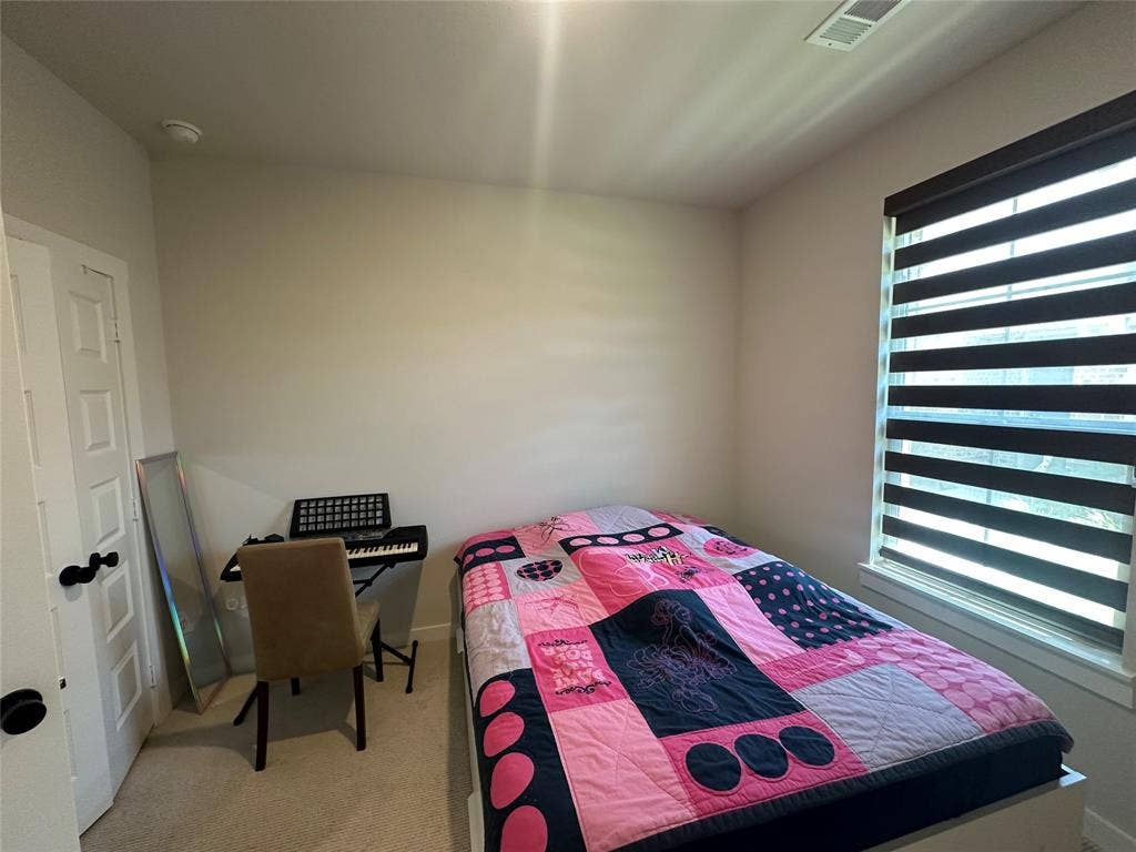 Window with layered shades, light-toned walls, and carpet flooring