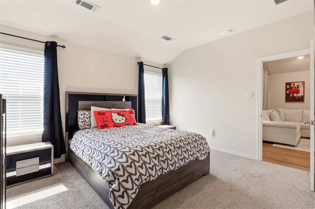 Bedroom featuring carpet flooring, two windows with blinds, and a built-in wall niche