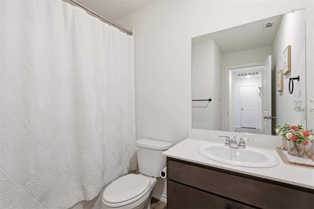 White vanity with dark wood-finish cabinetry, a white countertop, and an oval undermount sink