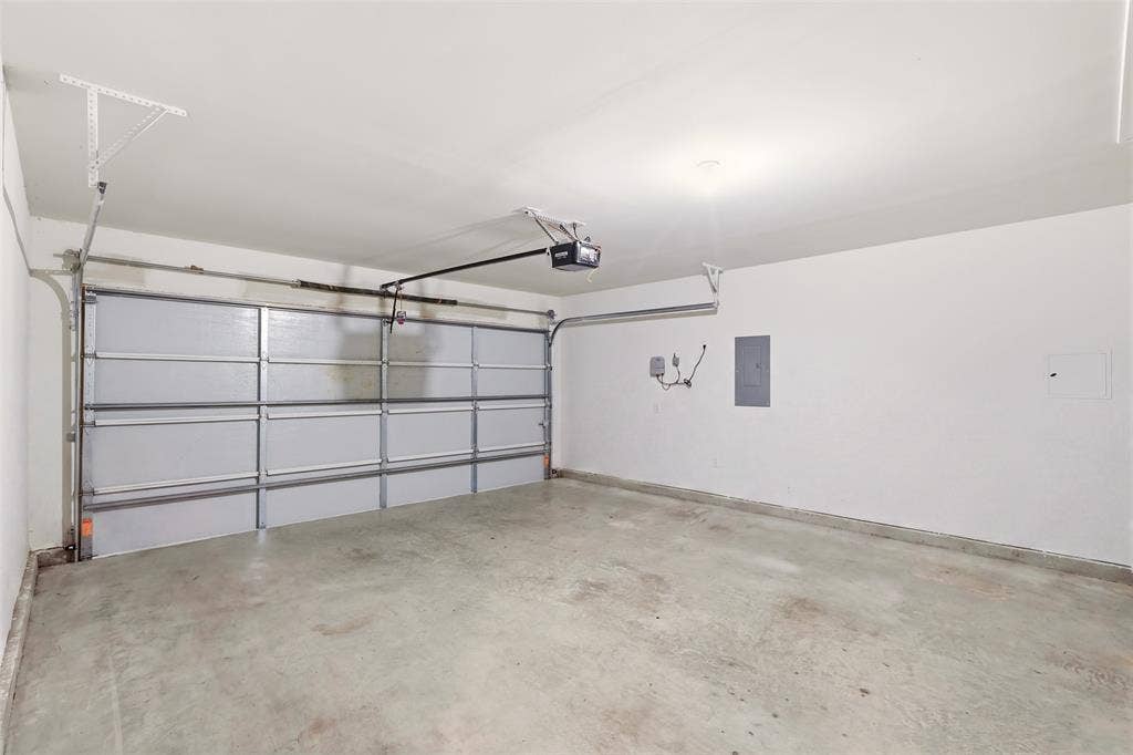 Attached garage with concrete flooring, automatic garage door opener, and white painted walls
