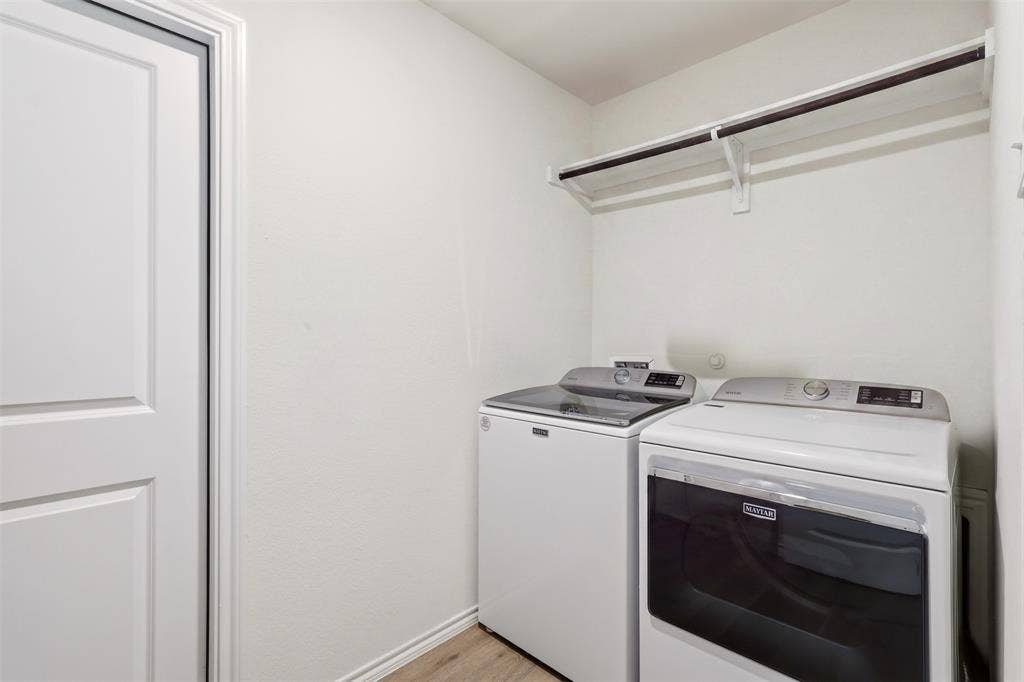 Laundry area with wood-finish flooring and a built-in hanging rod