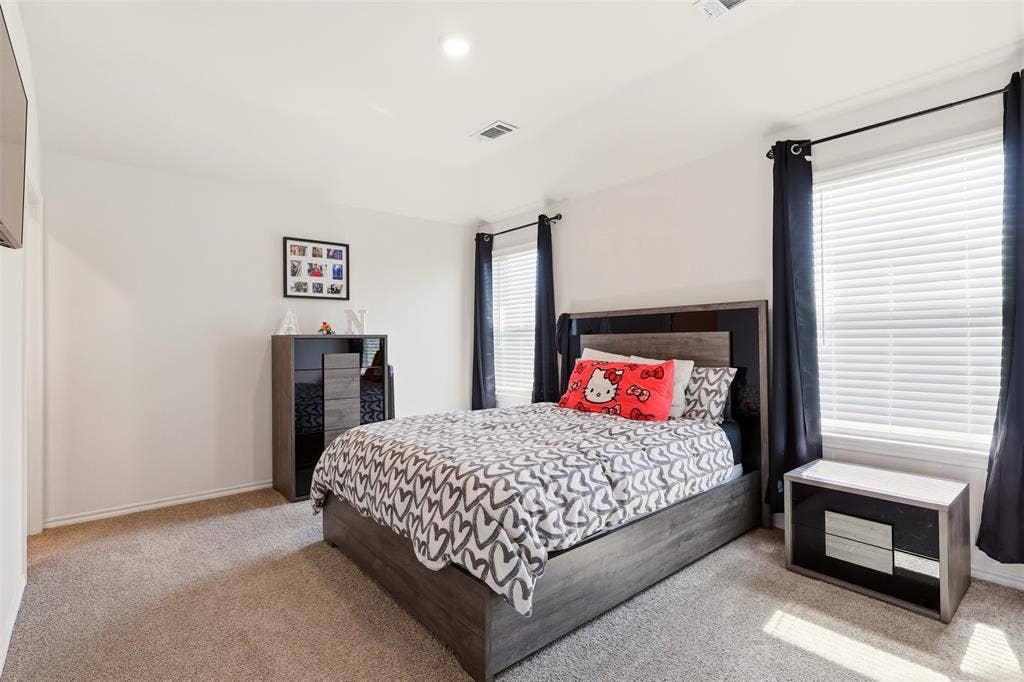 Neutral-toned carpeting, white walls, two windows with blinds and dark curtains, and a built-in ceiling light