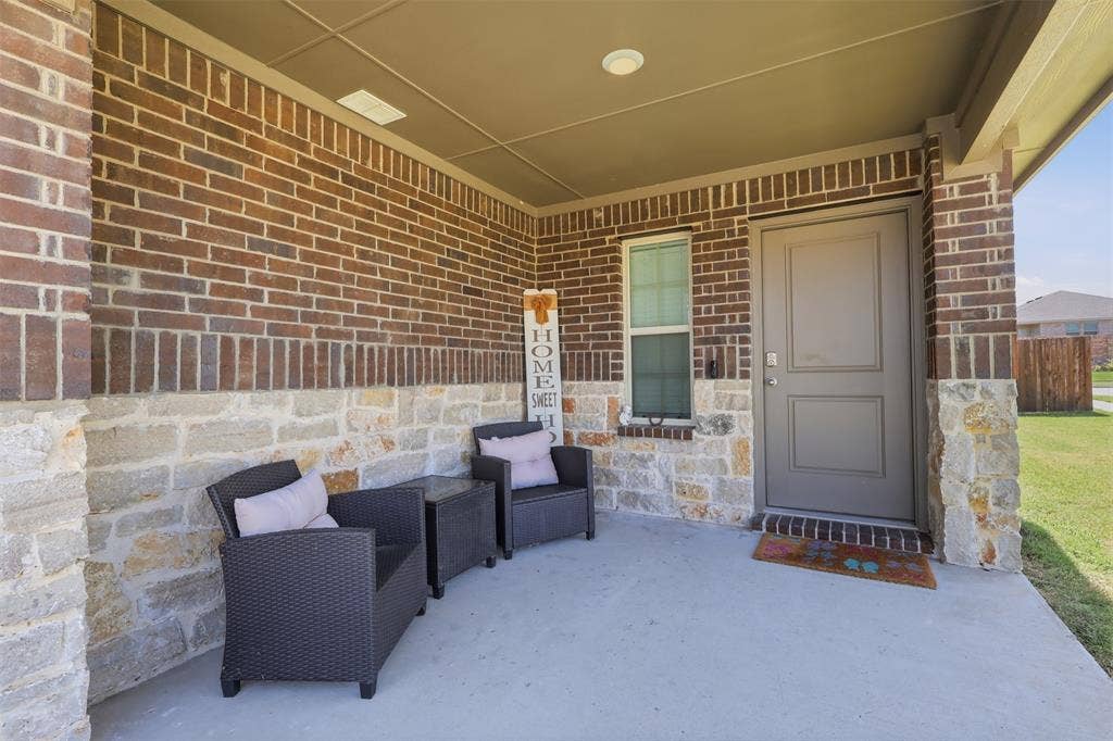 Brick exterior front porch with stone accents, covered entry, and a paneled front door