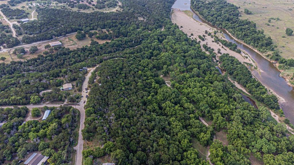 3018 River View Court, Granbury, TX 76048 Riverfront property featuring extensive tree coverage, natural waterways, and unpaved roads