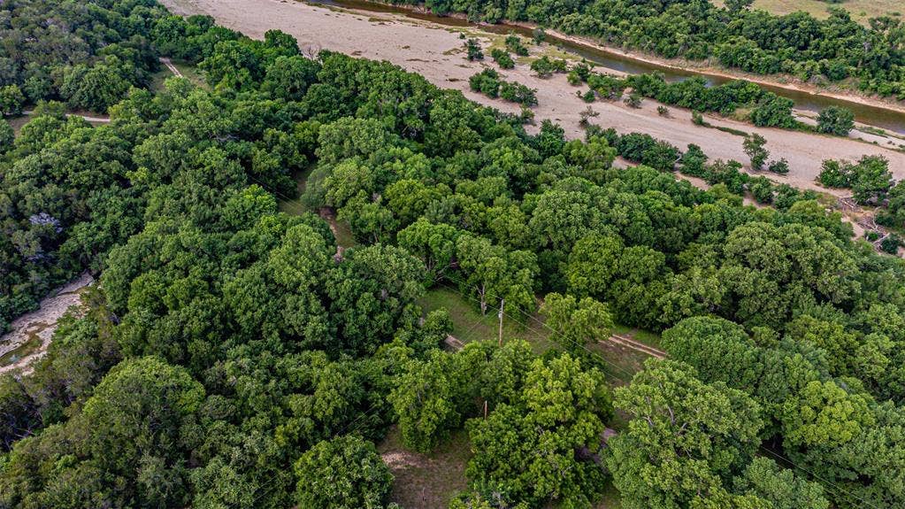 3018 River View Court, Granbury, TX 76048 Expansive natural acreage featuring a dense tree canopy, a meandering river, and a light-colored riverbed