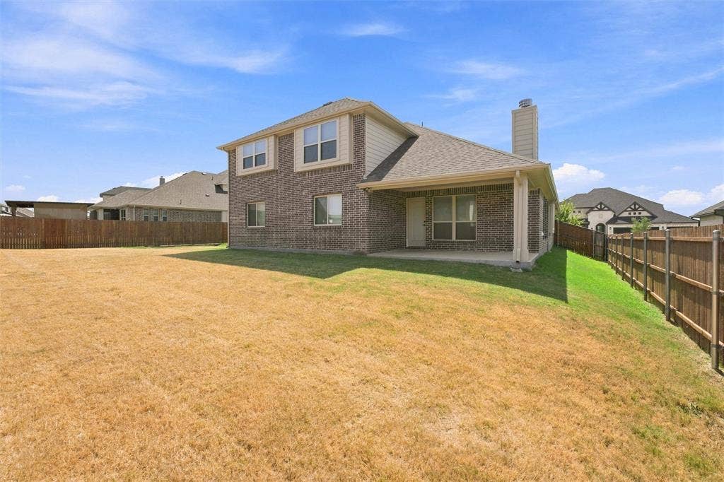 5225 Rowlan Row, Midlothian, TX 76065 Brick Colonial residence with dual gable rooflines and arched entryway, featuring a spacious rear yard with mature landscaping, wooden privacy fencing, and freshly sodded lawn