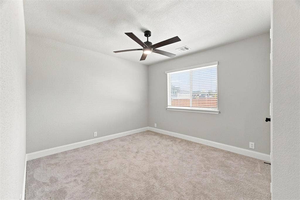 5225 Rowlan Row, Midlothian, TX 76065 Spacious bedroom with neutral wall finishes, plush carpeting, and abundant natural light from a large window with plantation shutters