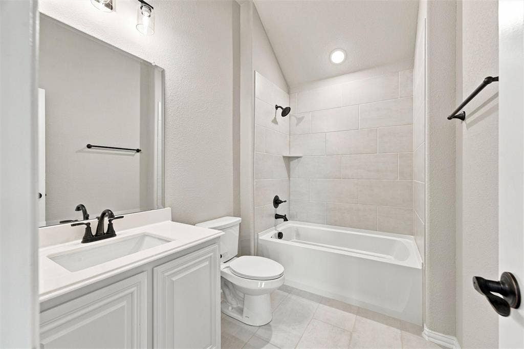 5225 Rowlan Row, Midlothian, TX 76065 Spa-inspired bathroom featuring a white vanity with dual sinks and matte black hardware, subway tile surround, recessed lighting, and an alcove bathtub with glass enclosure and matching matte black fixtures