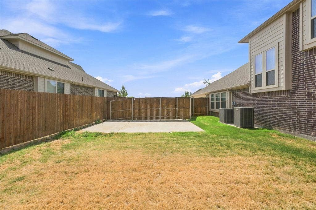 5225 Rowlan Row, Midlothian, TX 76065 Spacious backyard featuring a freshly poured concrete patio, mature landscaping with established lawn areas, and sturdy wood-finish privacy fencing