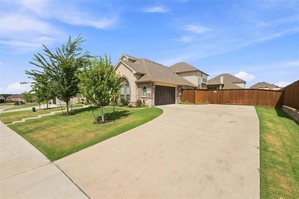 5225 Rowlan Row, Midlothian, TX 76065 Brick and stone exterior with arched window, concrete driveway, attached garage with wood-finish door, and privacy fencing