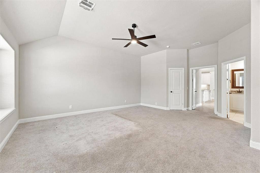 5225 Rowlan Row, Midlothian, TX 76065 Spacious primary suite featuring neutral carpet flooring, ceiling fan with integrated lighting, and multiple glass-panel doors providing natural light from adjoining spaces