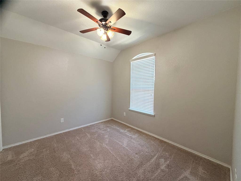 4103 Portrush Drive, Heartland, TX 75126 Vaulted ceiling with a ceiling fan, arched window, and neutral wall paint