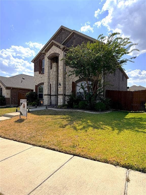 4103 Portrush Drive, Heartland, TX 75126 Brick and stone facade with arched entry, complementing the dark wood shutters and side-facing garage